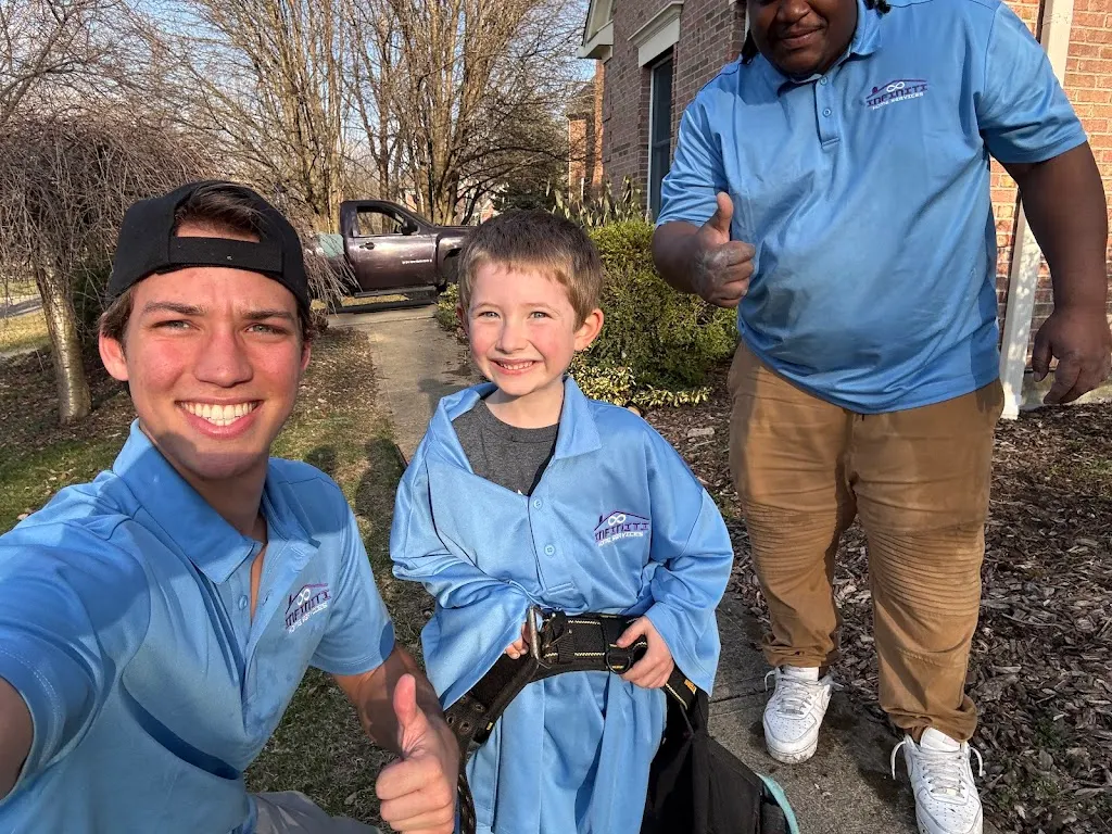 Two crew members and a young customer in a matching shirt giving a thumbs up