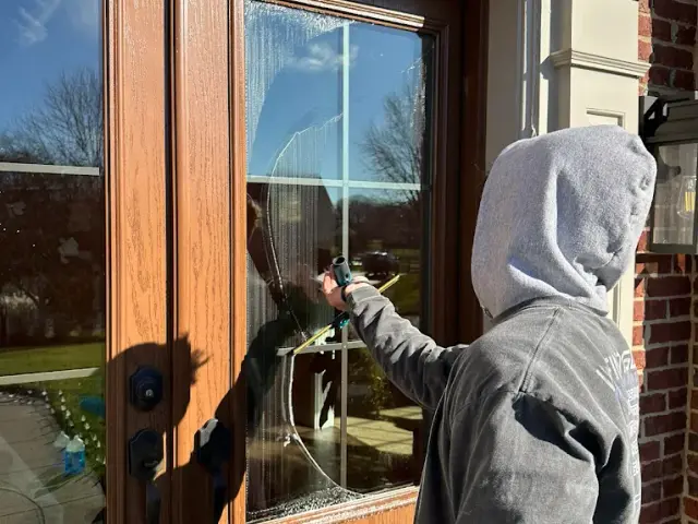 Technician squeegeeing the glass of a wooden front door