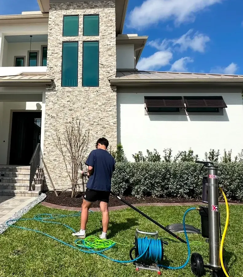 Technician washing the stone and stucco front of a two-story home