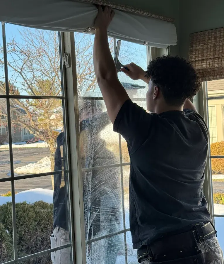 Technician squeegeeing the inside of a large window