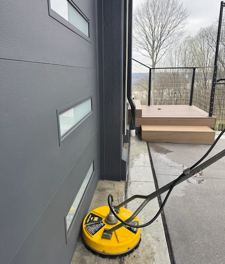 Surface cleaner on a concrete walkway beside a grey house