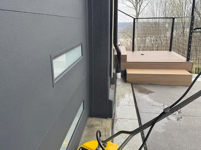 Surface cleaner on a concrete walkway beside a grey house