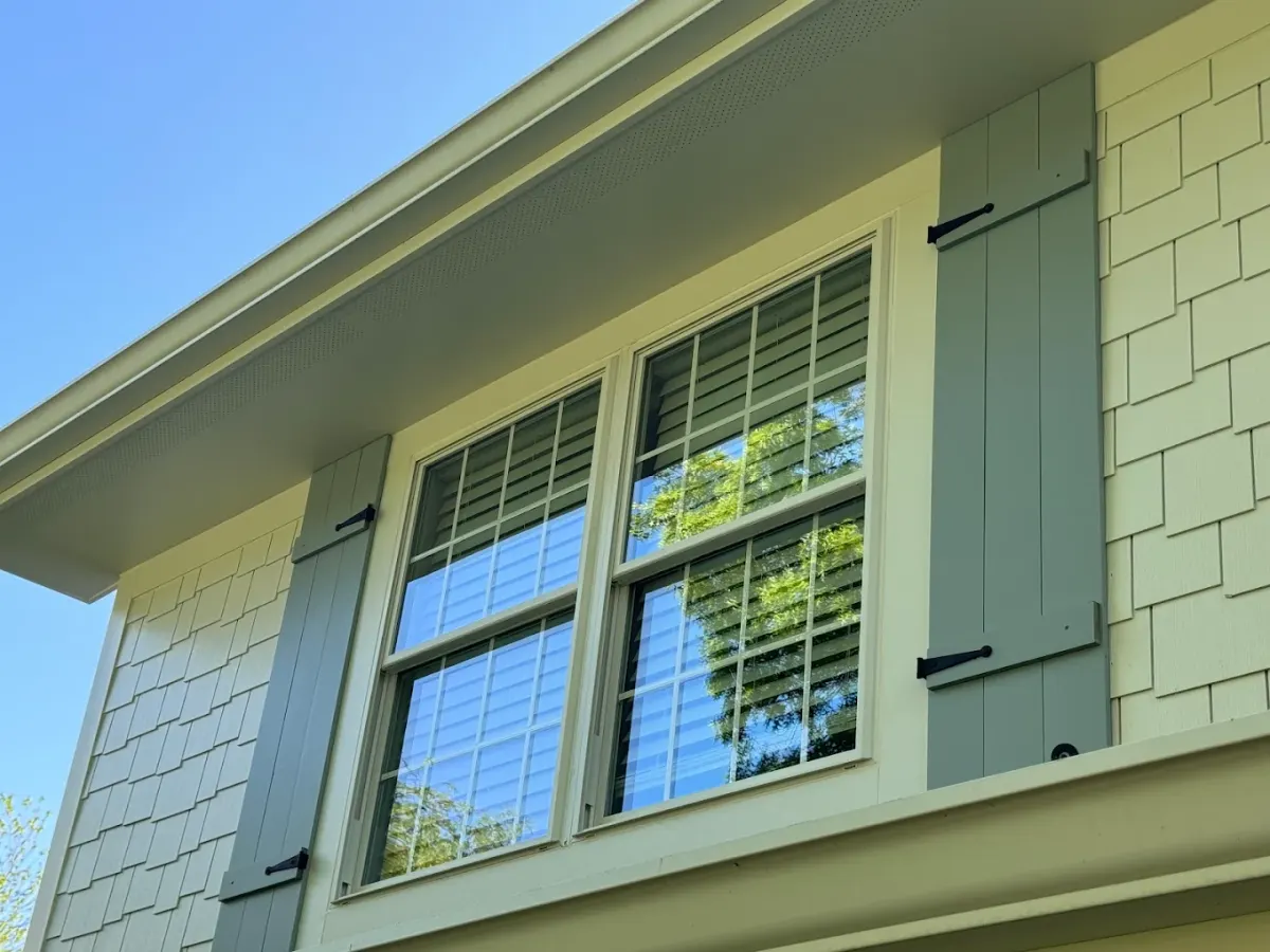 Clean double-hung window with green shutters after service